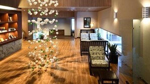 A spacious lobby with a wooden floor, a reception desk, seating area, and a unique ceiling light fixture. - Spa Esthetique Suichokan (Sapporo)