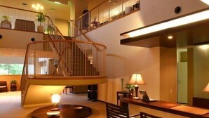 A spacious interior with a spiral staircase, a dining area with chairs, and a desk with a lamp. - Spa Esthetique Suichokan (Sapporo)