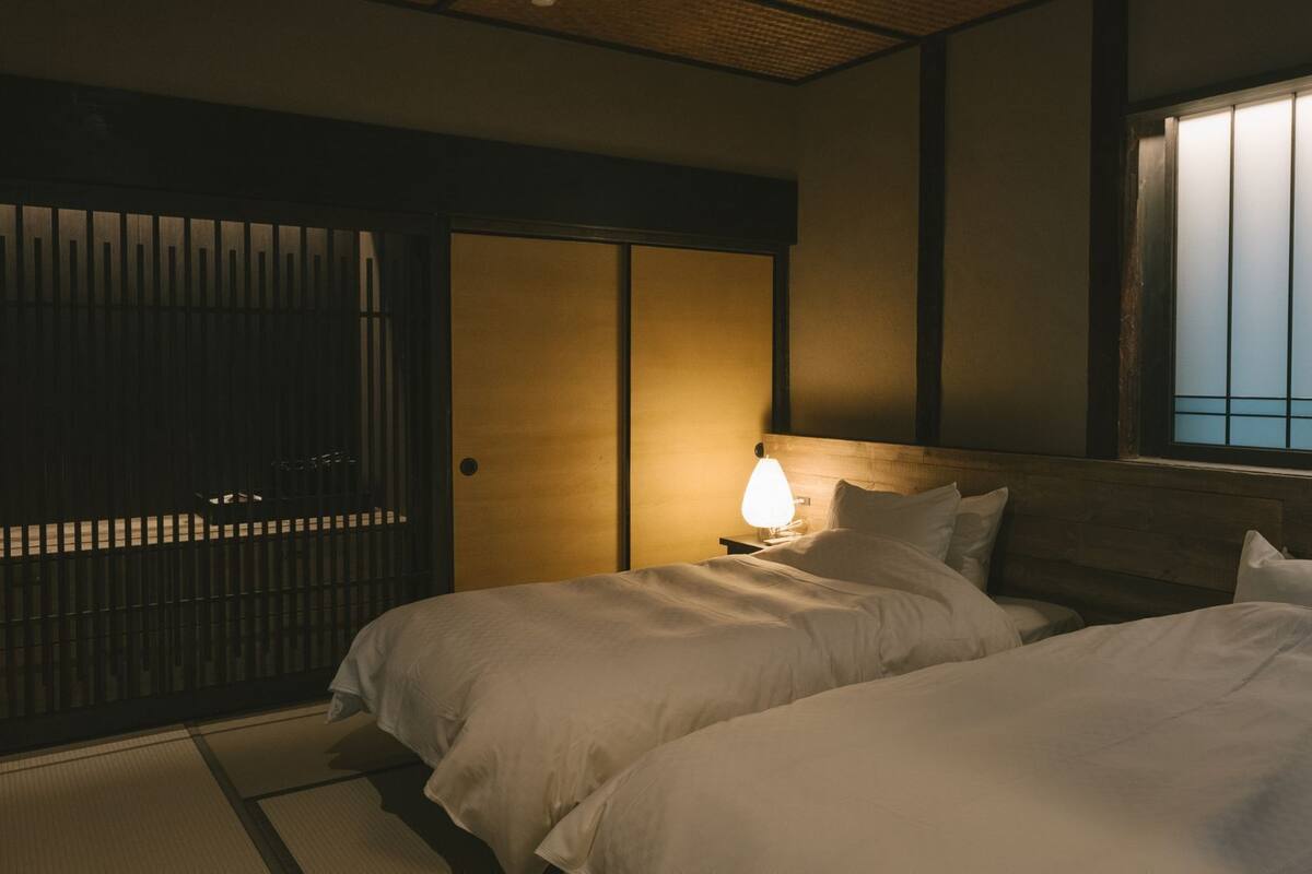 Ein traditioneller japanischer Raum mit Tatami-Boden, Shoji-Schirm und einem Bett mit Holz-Kopfstück.