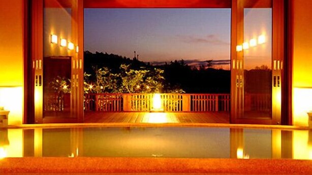 A hotel room with a large glass door leading to an outdoor deck.