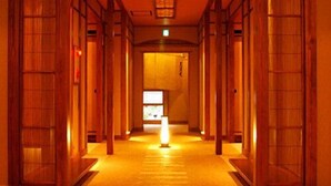A corridor with wooden doors, a carpeted floor, and a lit sign at the end.