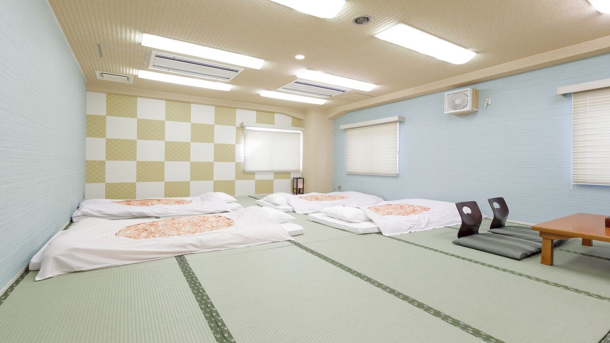 Quarto com quatro camas, uma mesa, cadeiras e um padrão quadriculado na parede.