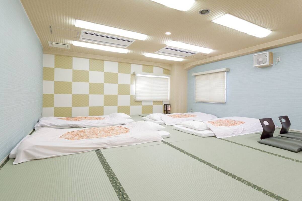 A room with four beds, a table, chairs, and a checkered wall pattern.