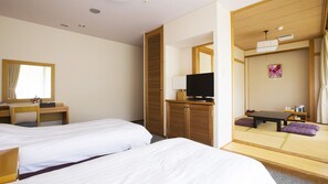 A hotel room with two beds, a desk with a chair, a television, and a traditional Japanese tatami mat seating area. - Hotel Tango Okoku (Kyotango)