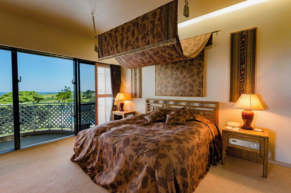 Une chambre dotée d’un grand lit, de deux tables de chevet avec des lampes, d’une petite table avec un téléphone et offrant une vue sur l’extérieur grâce à une porte-fenêtre coulissante.