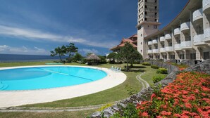 A hotel with a large swimming pool, a beach view, and a tower structure. - Southern links resort hotel (Yaese)