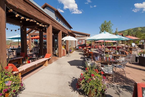 An outdoor patio area with wooden seating, tables, and umbrellas.