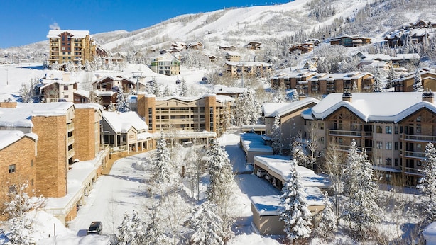 A snow-covered resort with multiple buildings, including a large hotel with a ski lift in the background. - CX113 | Onsite Check-In | Direct Access to Ski Area | Winter Shuttle | Hot Tub (Steamboat Springs)