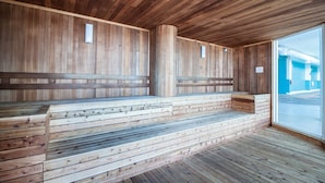 Eine Sauna mit Holzbänken und einer Glastür, die nach draußen führt.