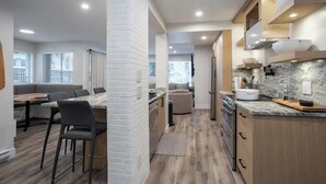 Une cuisine moderne dotée d’un plan de travail en marbre, de meubles en bois et d’un four encastré.