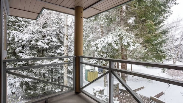 Un balcon doté d’une balustrade en métal, donnant sur un paysage enneigé parsemé d’arbres.