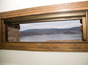 Ein Fenster mit Blick auf einen See und Berge.