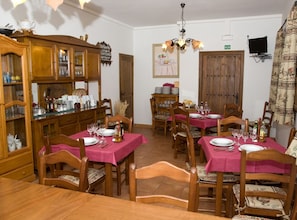 Ein Esszimmer mit Holzzimmermöbeln, rosafarbenen Tischdecken und einem Kronleuchter.