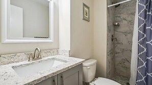 A bathroom with a marble sink, a toilet, and a shower with a patterned curtain.