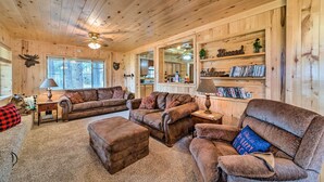 Interior acogedor de una cabaña con paredes de madera, una chimenea y una zona de estar confortable con sofás y una mesa de centro.