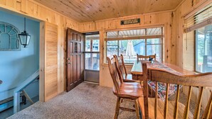 Interior de madera con una mesa de comedor y sillas, un ventilador de techo y vistas al exterior.