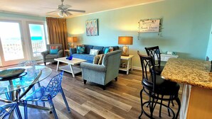 A living room with a sofa, chairs, a coffee table, and a dining area with a glass table and chairs. - Beachfront Stay with Amazing Views (Destin)
