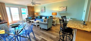 A living room with a sofa, chairs, a coffee table, and a dining area with a glass table and chairs.
