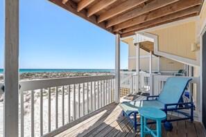Une terrasse en bois avec une balustrade blanche donnant sur une plage.