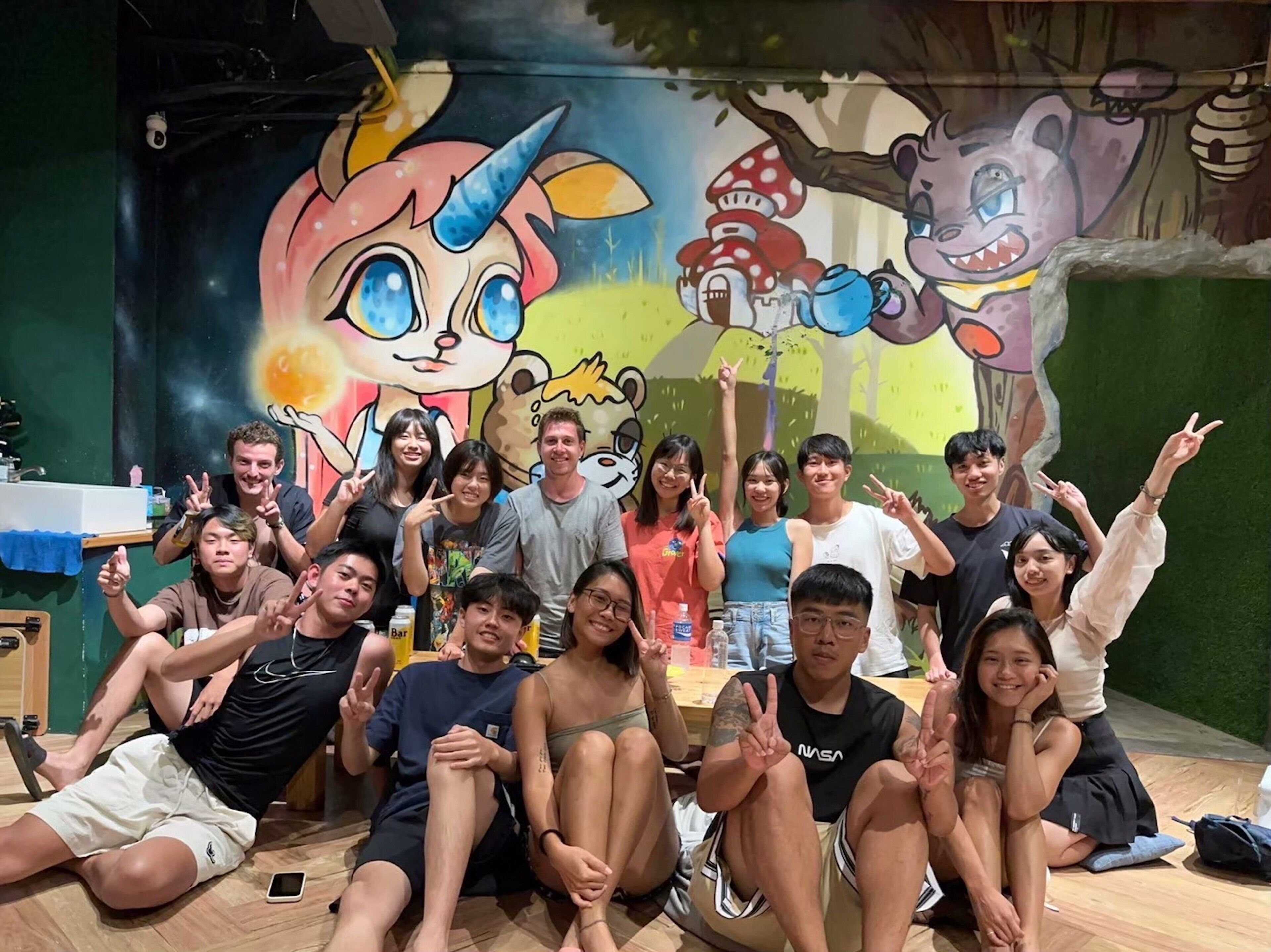 A group of people posing in front of a mural with cartoon characters.