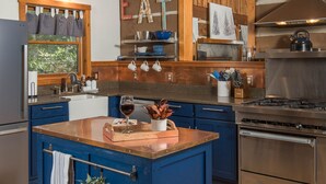 Une cuisine dotée d’un îlot central, d’un plafond en bois et d’appareils électroménagers en acier inoxydable.