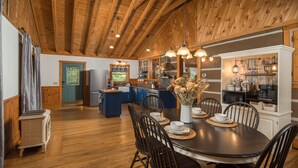 Une cuisine spacieuse avec des poutres en bois, un coin repas doté d’une table ronde et une vue sur l’extérieur.