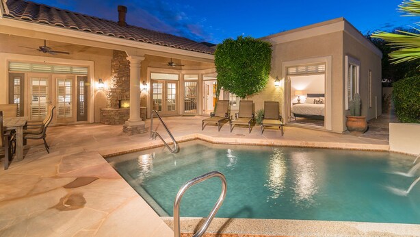 A pool area with a stone fireplace, outdoor seating, and a bedroom entrance. - A Beauty in Scottsdale! (Scottsdale)