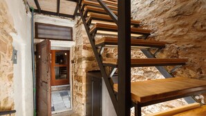 Ein rustikales Stein-Interieur mit einer Holztreppe, die in eine untere Ebene führt.