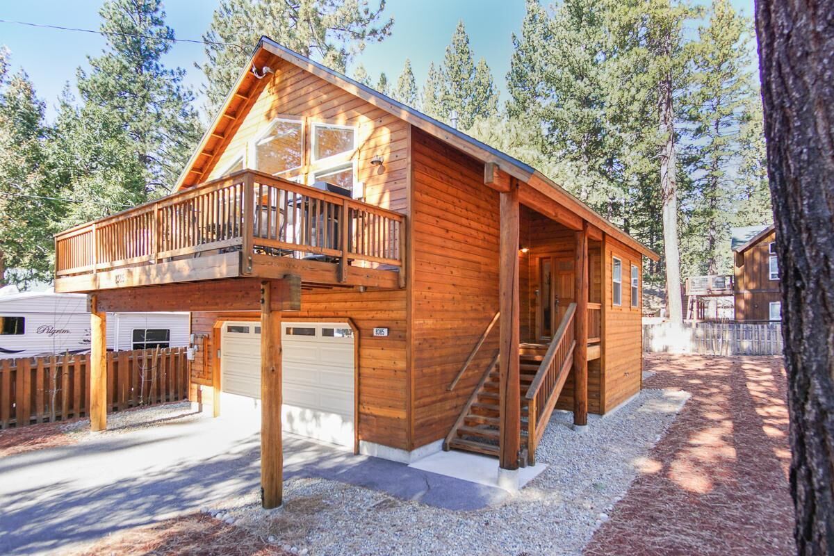 Una baita in legno con un balcone, un garage e una scala che porta all'ingresso principale.