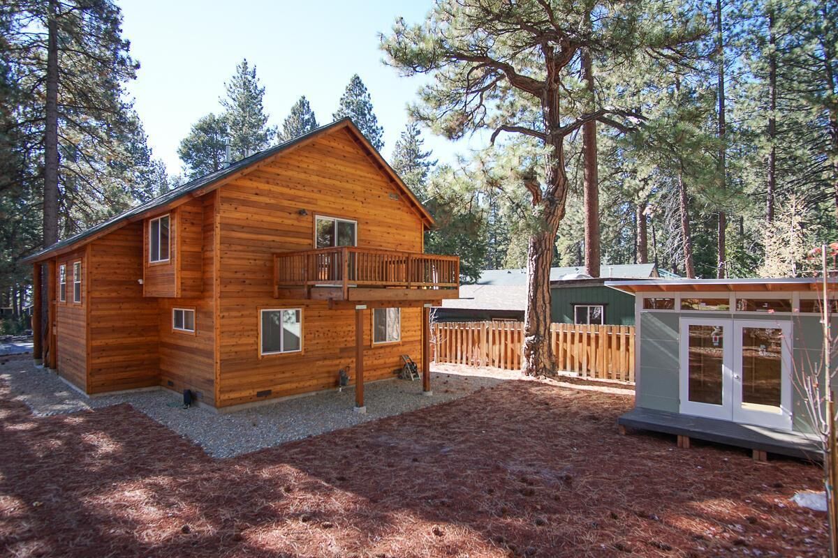 A wooden cabin with a balcony, surrounded by trees.