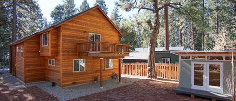 A wooden cabin with a balcony, surrounded by trees.