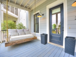 A porch with a swing seat, a door, and a window.