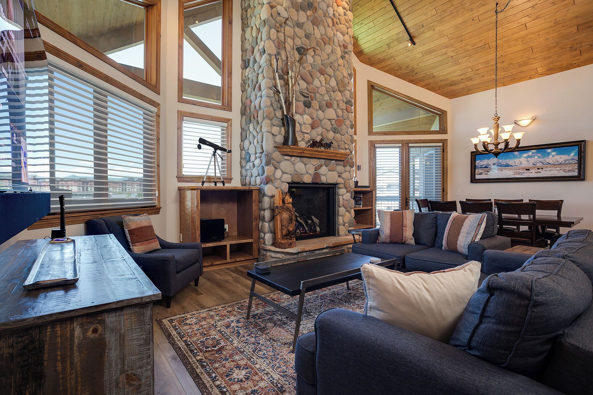 A spacious living room with a stone fireplace, large windows, and a cozy seating area.