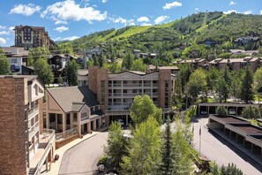 A multi-story hotel with a central courtyard, surrounded by lush greenery and a mountainous backdrop.