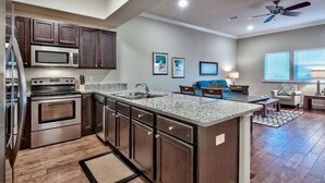 A modern kitchen with dark wood cabinets, stainless steel appliances, and a granite countertop.