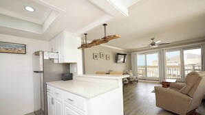 Une cuisine moderne avec des meubles blancs, un îlot central intégré et un ventilateur de plafond.