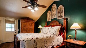Ein Schlafzimmer mit einem hölzernen Bett, zwei Nachttischlampen, einem Deckenventilator und einem Holzschrank.