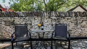 Ein Sitzbereich im Freien mit zwei Stühlen und einem Tisch vor einer Steinwand.