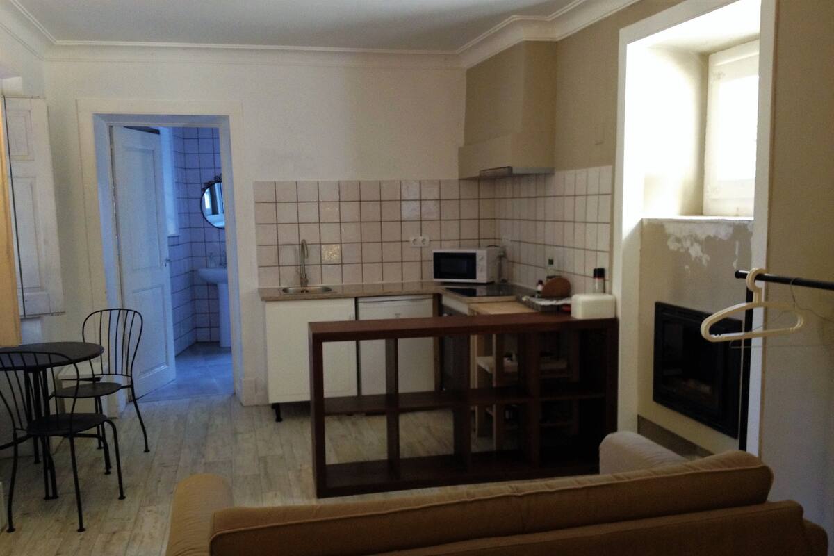A compact kitchen with a microwave, sink, and a small dining area with chairs.