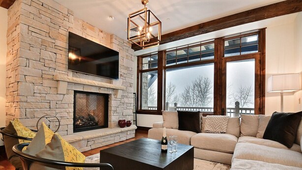 A living room with a stone fireplace, a sofa, a coffee table, and large windows.