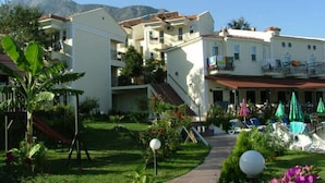 A hotel with multiple floors, outdoor seating, and a garden with a pathway.