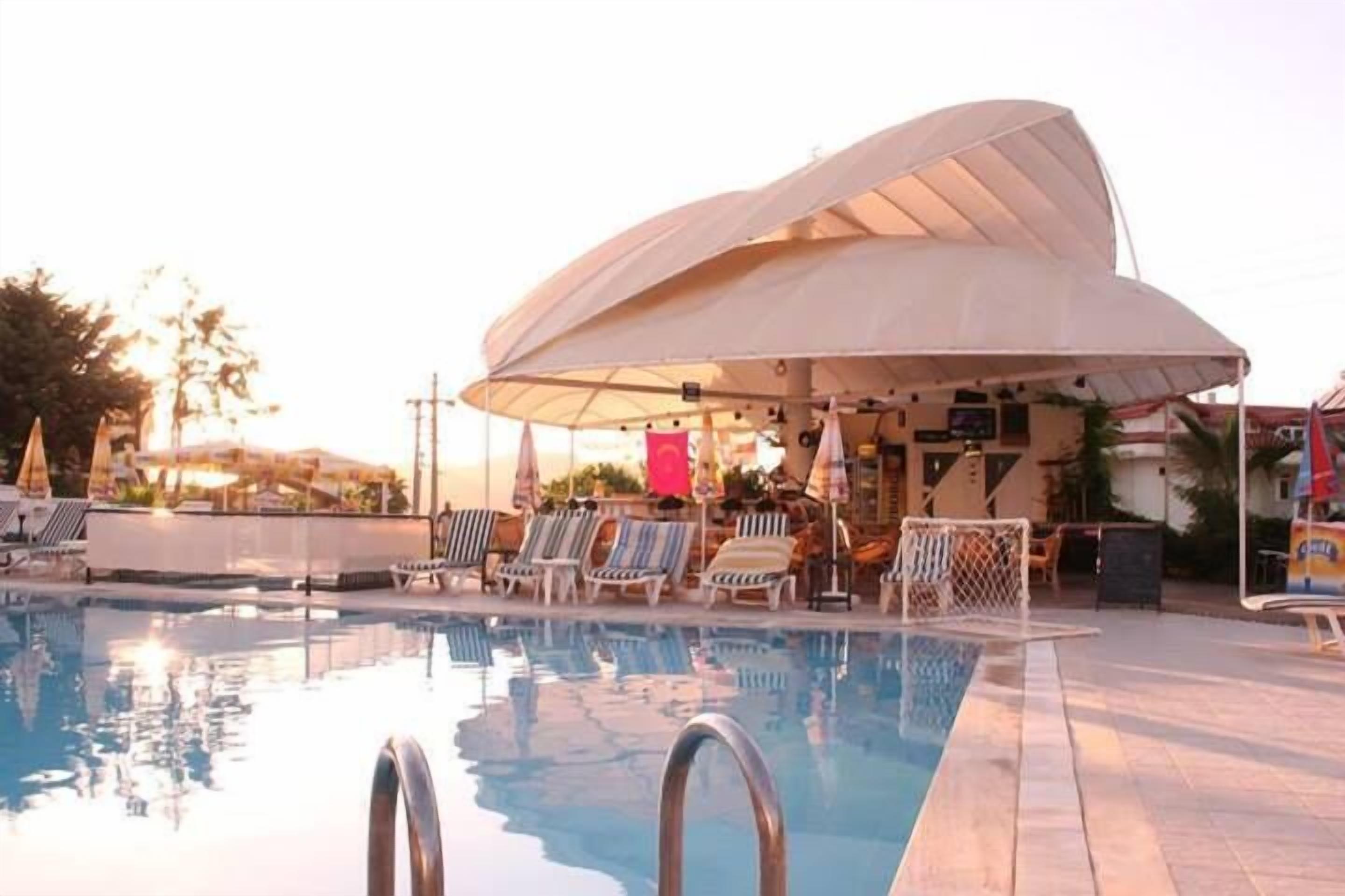 Piscina com espreguiçadeiras e guarda-sóis, área de estar coberta e vista para a paisagem ao redor.