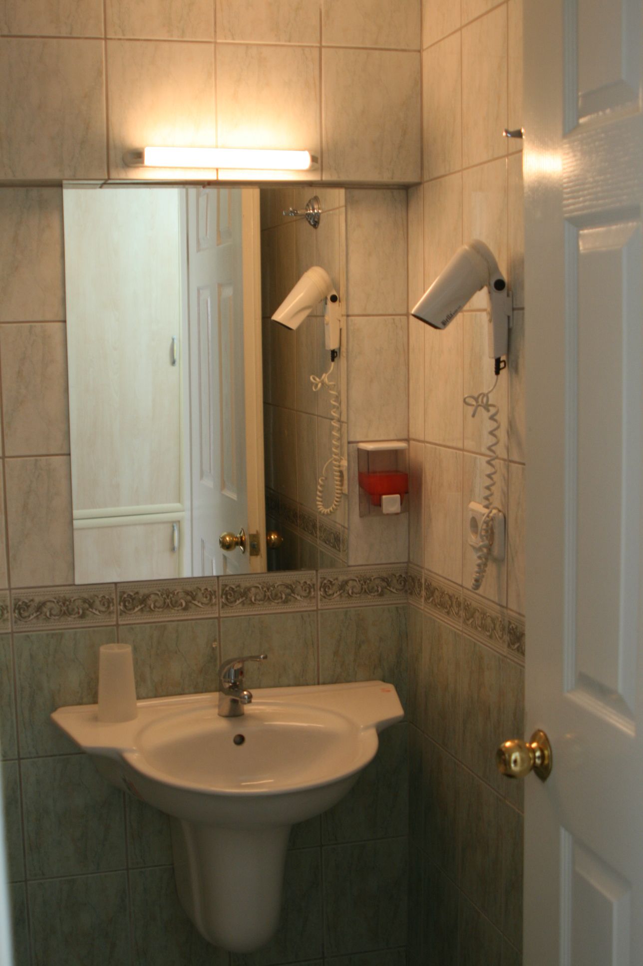 Casa de banho com lavatório, espelho, secador de cabelo e telefone.