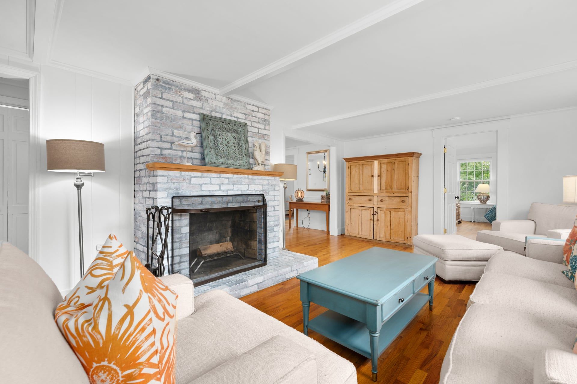 A living room with a fireplace, wooden flooring, and a light blue table.