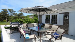 An outdoor patio with a grill, table, chairs, and an umbrella.