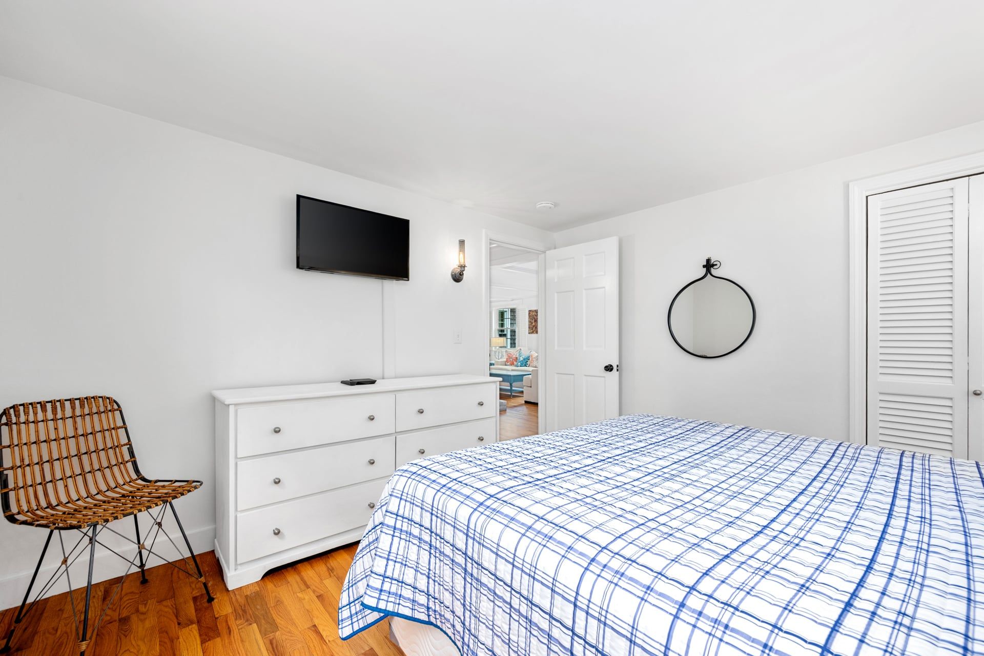 A bedroom with a bed, a dresser, a television, a chair, and a door.