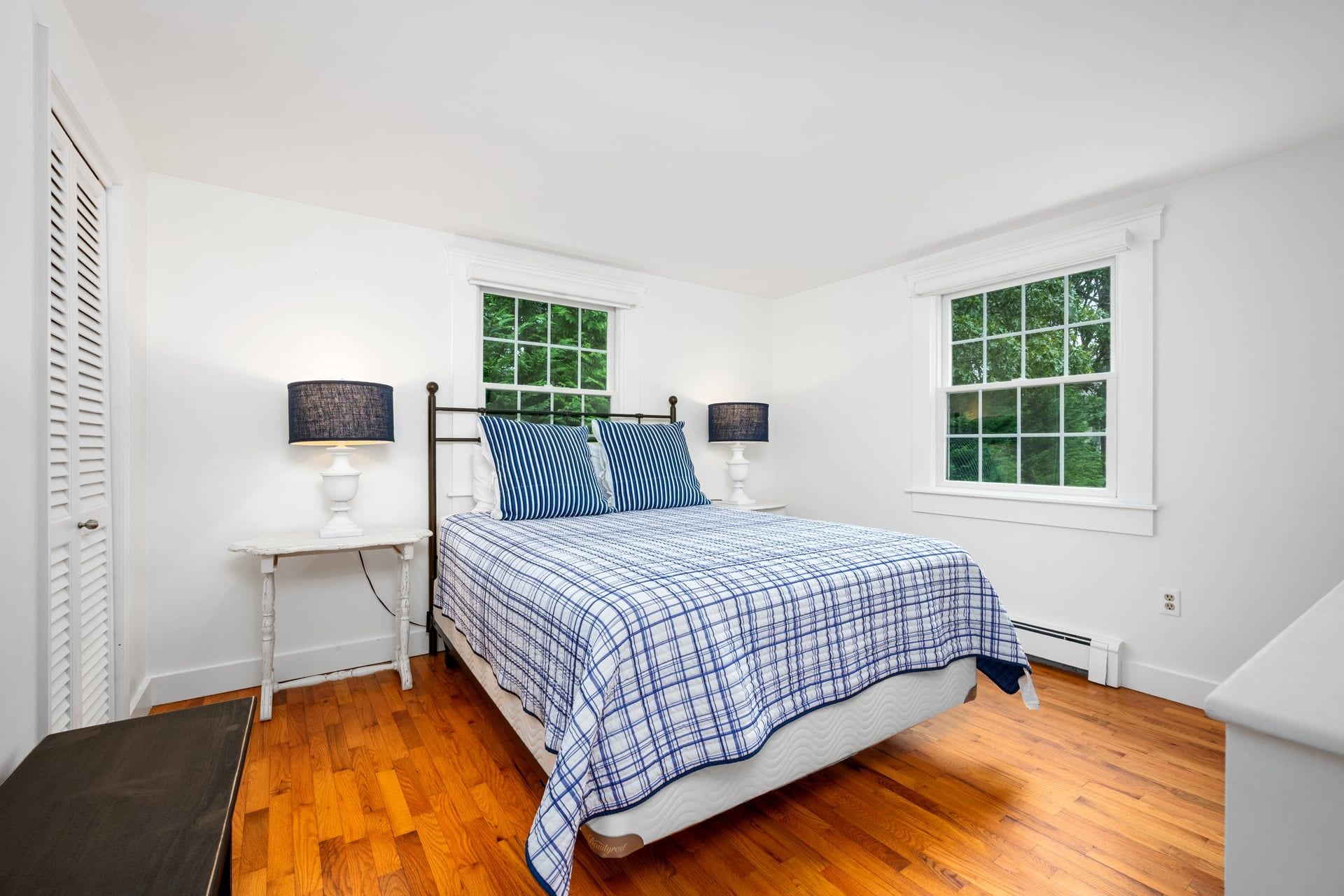 A bedroom with a bed, two bedside tables, two lamps, a window, and a door.