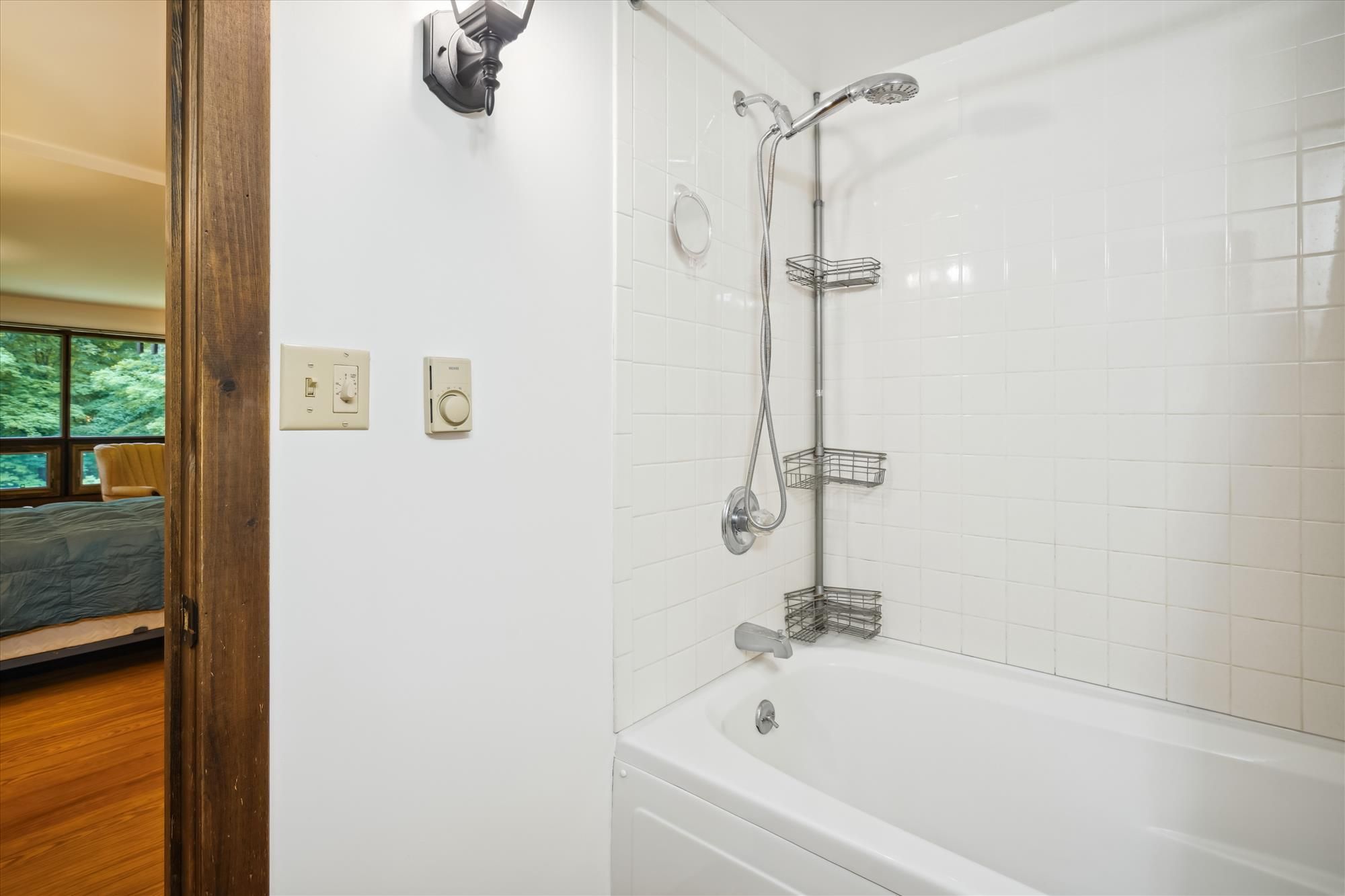 Un baño con bañera, ducha con cabezal de ducha de mano y perchero.