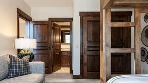 Una habitación con un sofá gris, una lámpara y una puerta de madera con un espejo.