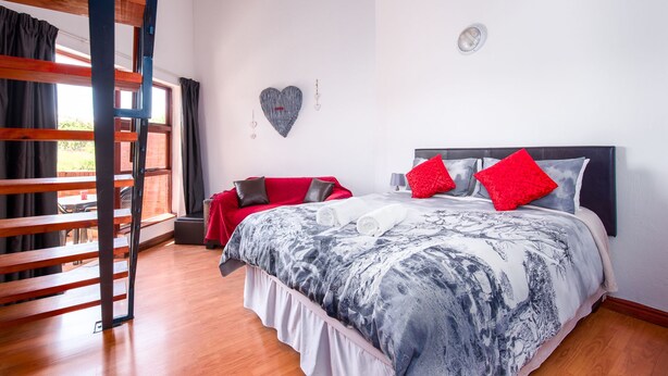 A bedroom with a bed, a bench, a window, and a wall decoration.